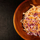 Wooden bowl with coleslaw on a dark background
