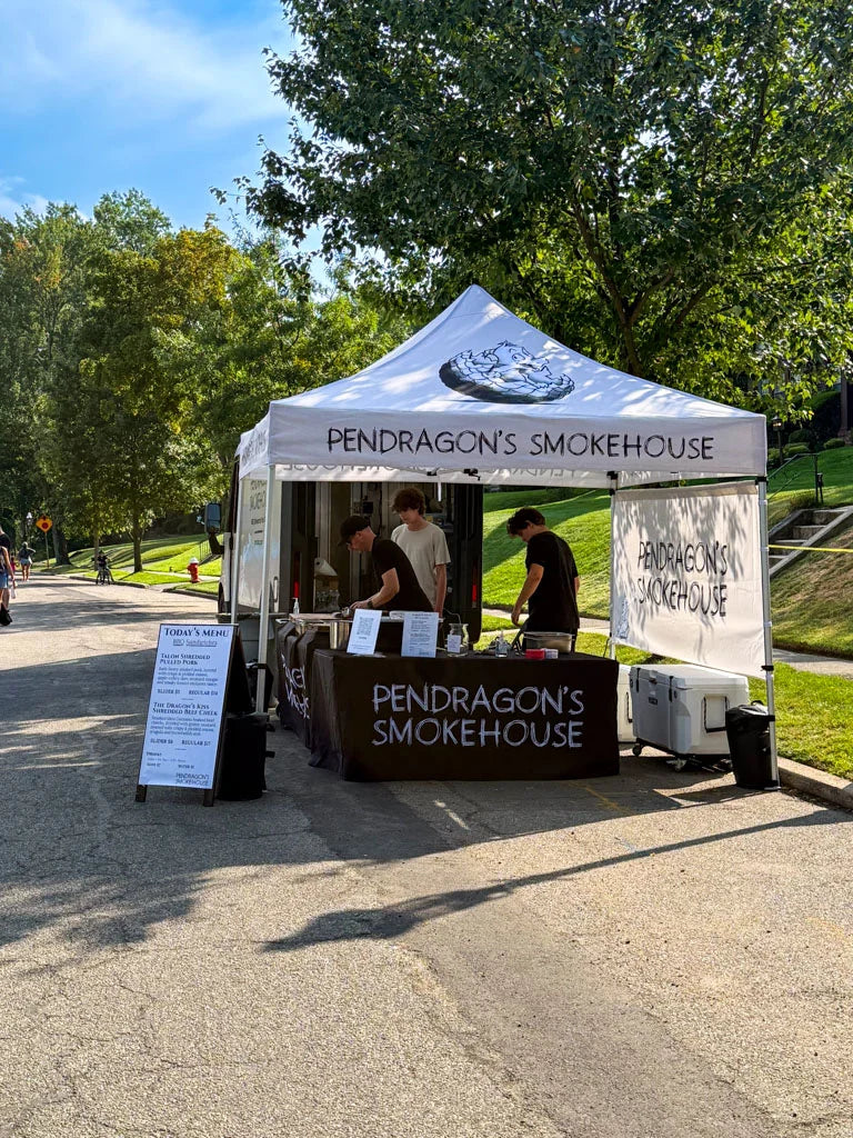 Pendragon’s Smokehouse canopy setup on a Montclair residential street with the delivery van in the background, ready to serve neighborhood catering guests.
