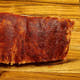 Two-thirds of a raw Pen’s House rib rack covered in dry rub, angled off-frame before cooking