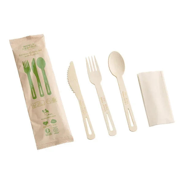 A bamboo cutlery pack including a fork, knife, spoon, and napkin, packaged in a clear plastic pouch with green accents and text.