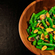 Wooden bowl filled with green beans and almonds on a dark background