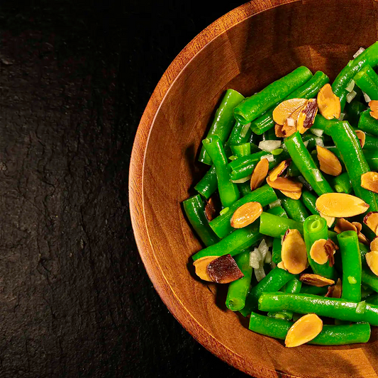 Wooden bowl filled with green beans and almonds on a dark background