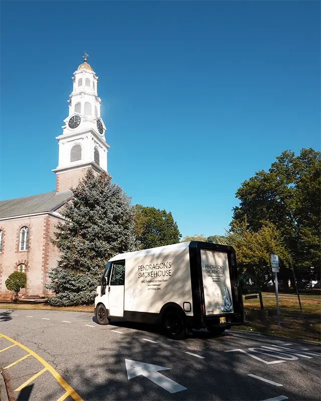 Electric delivery van in front of Church in Bloomfield  NJ with 'Pendragon's Smokehouse' branding.