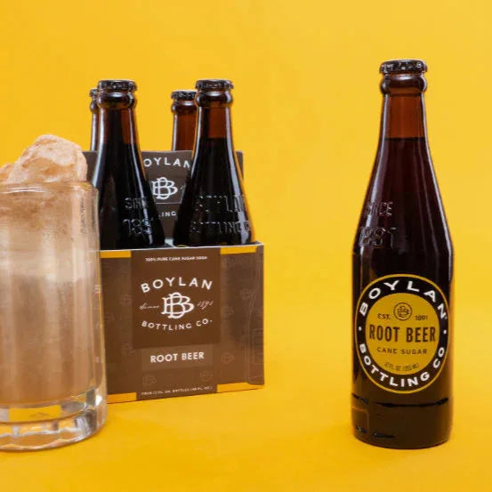 A 12oz bottle of Boylan Root Beer with a glass of root beer float in the background, and a pack of Boylan root beer bottles visible.