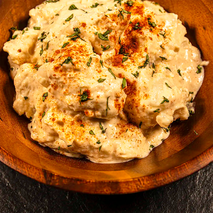 Creamy potato salad in a wooden bowl on a dark background
