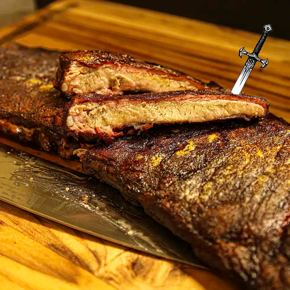 Sliced rack of Dragon’s Breath #3 ribs with visible char and spice, ready for BBQ delivery from Pendragon’s Smokehouse
