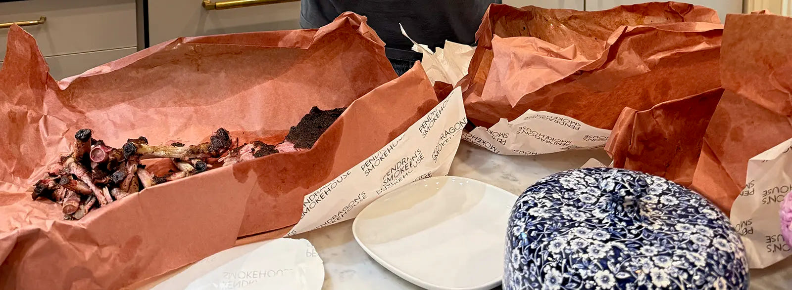 Branded Pendragon’s Smokehouse delivery wrapping partially unpacked with finished ribs, post-delivery moment
