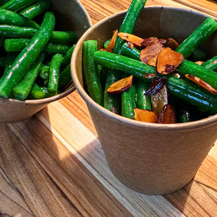 Green beans with roasted almond flakes, shallots and garlic, finished with lemon zest and served in a hot side container