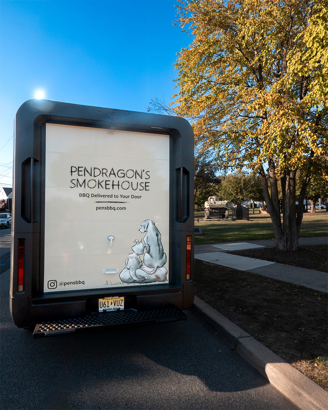 Pendragon's Smokehouse advertisement on a vehicle in an outdoor setting with trees and blue sky and a tank in Little Falls NJ