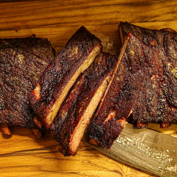 Sliced rack of Pen’s House ribs with two meaty bones placed on top, prepared for BBQ delivery in New Jersey