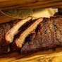 Sliced rack of Smokehouse Select ribs with two meaty bones stacked on top, prepared for BBQ delivery in New Jersey