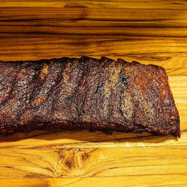 Two-thirds of a rack of Smokehouse Select ribs, sauced and sliced with the edge trailing out of frame