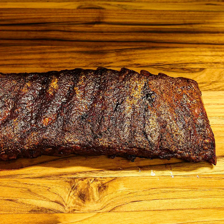 Two-thirds of a rack of Smokehouse Select ribs, sauced and sliced with the edge trailing out of frame