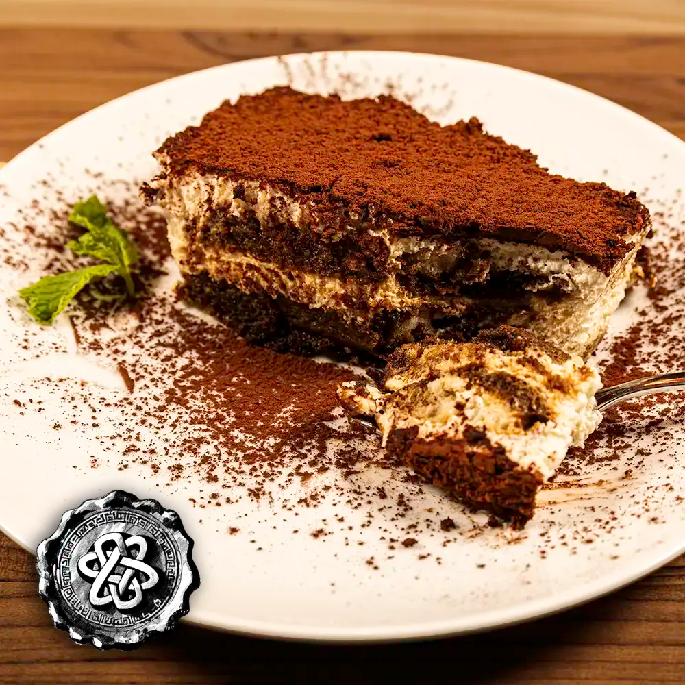 Slice of tiramisu dessert on a white plate with a decorative medieval seal in the corner